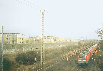 An Wohnhäusern vorbeiführende Bahntrasse mit Stromleitung in Altglienicke