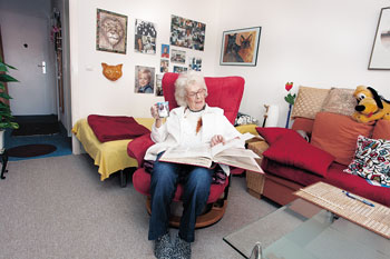 Seniorin auf einem Sessel in ihrer Wohnung