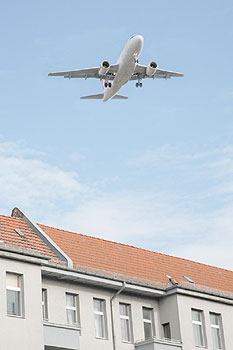 Über die Dächer von Wohnhäusern fliegendes Flugzeug