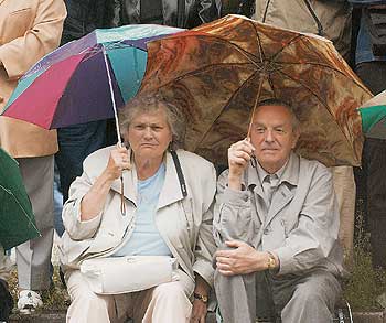 Seniorenpaar unter Regenschirmen