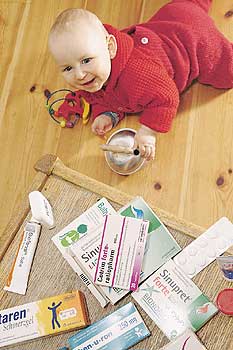 Kleinkind, krabbelnd vor einem niedrigen Tisch mit Medikamenten-Packungen