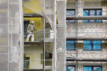 Bauarbeiter auf einem Gerüst bei der Außenwand-Isolierung eines Gebäudes