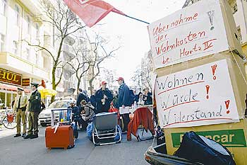 Protestplakate mit den Inschriften 'Übernahme der Wohnkosten bei Hartz IV' und 'Wohnen! Würde! Widerstand!'