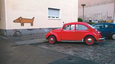 Knallroter VW-Käfer vor Hauswand