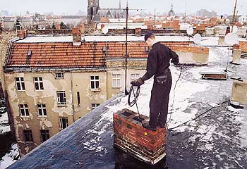 Schornsteinfeger auf dem Dach eines Hauses beim Reinigen eines Schornsteins