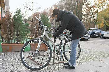Ein Fahrrad wird auf der Straße an einen Fahrradständer angeschlossen