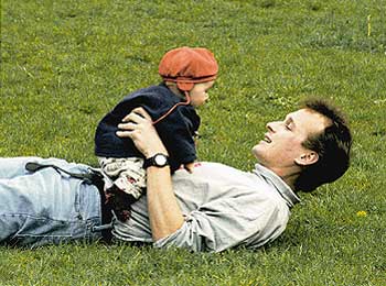 Ein junger Vater tollt mit seinem Sohn auf einer Wiese herum