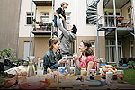 Zwei Frauen auf einem Berliner Hinterhof, im Hintergrund tobt ein Vater mit seinem Kind