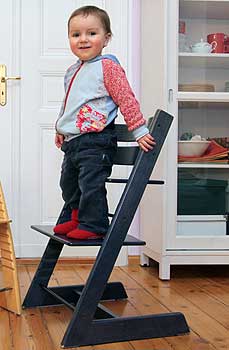 Ein Kleinkind steht auf einem Stuhl, dessen Höhe eingestellt werden kann