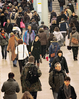 Zahlreiche Menschen bewegen sich in einer Bahnhofshalle