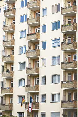Übereinandergeschichtete Balkone an einer Hausfassade, auf dem untersten Balkon wehen drei Fähnchen: Deutschland, Berlin und Hertha