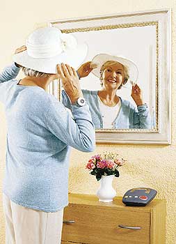 Funksender am Handgelenk einer Seniorin, die in einen Spiegel schaut
