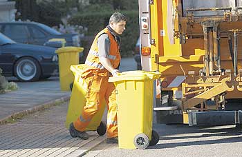 Ein Arbeiter schiebt eine Gelbe Tonne zu einem Müllwagen