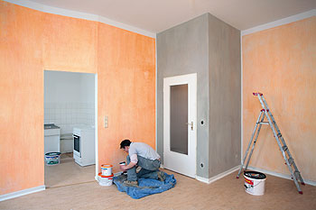 Ein Maler streicht Wände in warmen Farbtönen