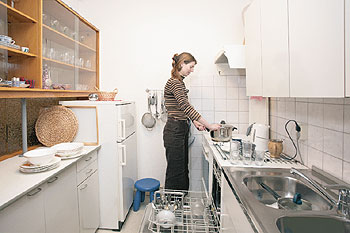 Eine Frau bei Haushaltsarbeiten in einer engen Küche
