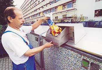 Ein Mann entsorgt einen Beutel Müll in einer Müllschleuse