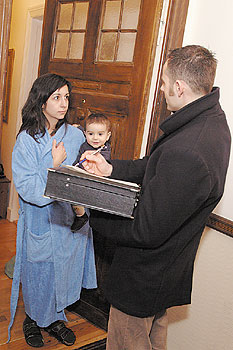 Vermieter und Mieterin mit Kind auf dem Arm zwischen Tür und Angel