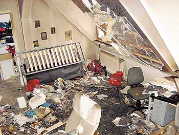 Beschädigter Hausrat in einem Zimmer mit zerstörtem Dachfenster