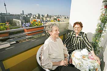 Zwei Seniorinnen auf ihrem Balkon mit Sicht über die Stadt
