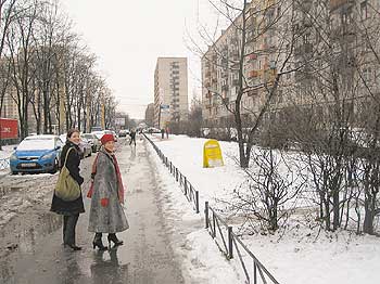 Zwei Frauen auf einer verschneiten Straße zwischen Plattenbauten