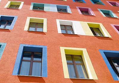 Bunte Fenster an eine sanierten, rot gestrichenen Hausfassade