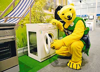 Der Gasag-Bär sitzt lachend vor einer Waschmaschine