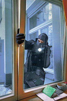 Ein Einbrecher macht sich am angekippten Fenster zu schaffen