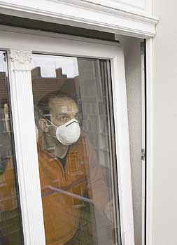 Mann mit Gesichtsmaske öffnet Fenster zum Lüften