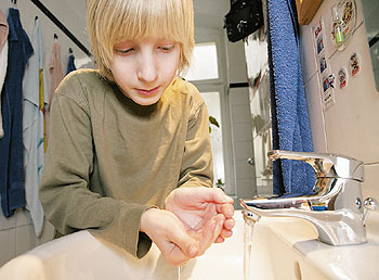 Ein Kind wäscht sich die Hände unter einem laufenden Wasserhahn