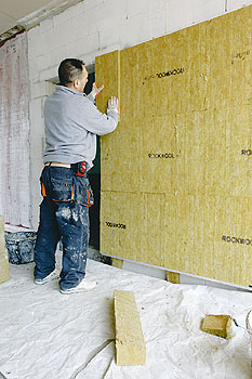 Ein Bauarbeiter beim Dämmen einer Wand