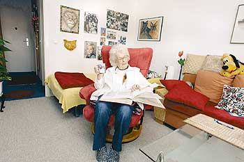 Seniorin sitzt in einem Sessel und liest ein Buch