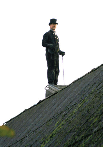 Schornsteinfeger bei der Arbeit auf einem Hausdach