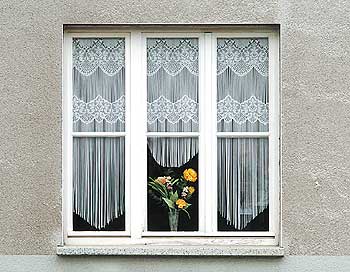 Fenster mit Gardine und Blumen auf dem Fensterbrett