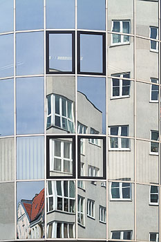 Spiegelnde Häuserfassade mit verschiedenen Fenstern