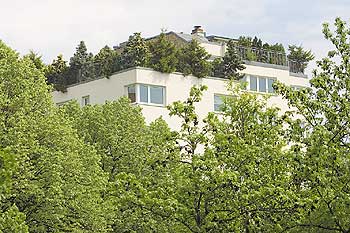 Gebäude mit Pflanzen auf dem Dach und Bäumen im Vordergrund
