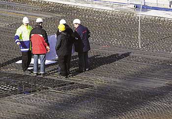 Männer mit Bauhelmen auf einem Darhtgeflecht-Dach einer Baustelle