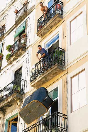 Umzug einmal anders: Zwei Männer auf Balkonen lassen ein Sofa an einem Seil herab