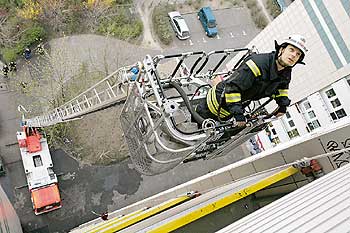 Feuerwehrmann auf einer ausgefahrenen Leiter an einer Hochhausfassade