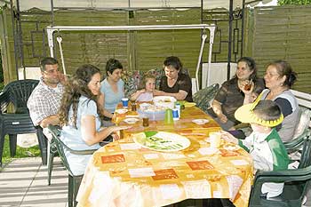 Familie Cakir und Angehörige essen an einem Tisch vor ihrer Laube