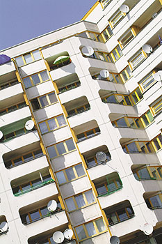Hochhaus mit Balkonen, auf denen TV-Schüsseln montiert sind