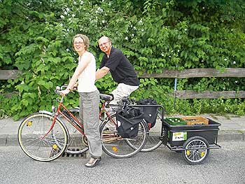 Junges Paar mit Fahrrad plus beladenem Anhänger