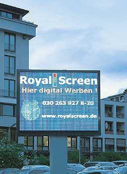 Großformatiger Werbebildschirm vor Wohnhäusern an einer Straße