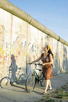 Frau mit Fahrrad vor einem Stück Mauerrest