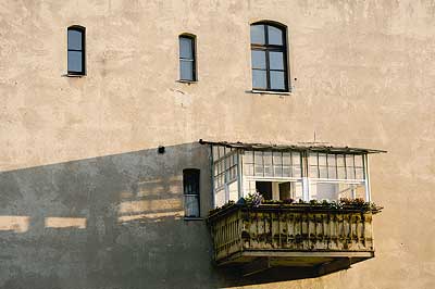 Ein überdachter Berliner Balkon an einer südländisch aussehenden Hausfassade