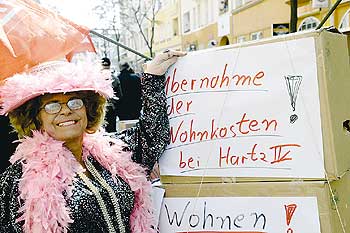 Demonstrantin mit einem Schild. Aufschrift: Übernahme der Wohnkosten bei Hartz IV!