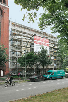 Eingerüstetes Wohngebäude mit Großplakat zum Verkauf von Eigentumswohnungen