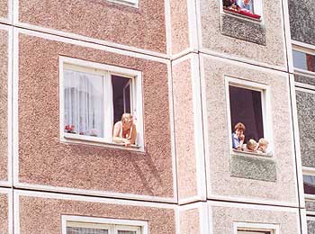 Mieter schauen aus den Fenstern ihrer Plattenbauwohnungen aus DDR-Zeiten