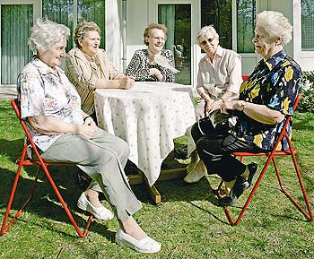Senioren sitzen an einem Tisch im Garten
