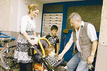 Hausmeister Klaus Dehne im Gespräch mit einer jungen Mutter mit Kind in Kinderwagen