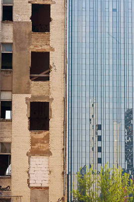 Fassaden eines Sanierungsgebäudes ohne Fensterrahmen direkt neben einer Glas-Neubaufassade